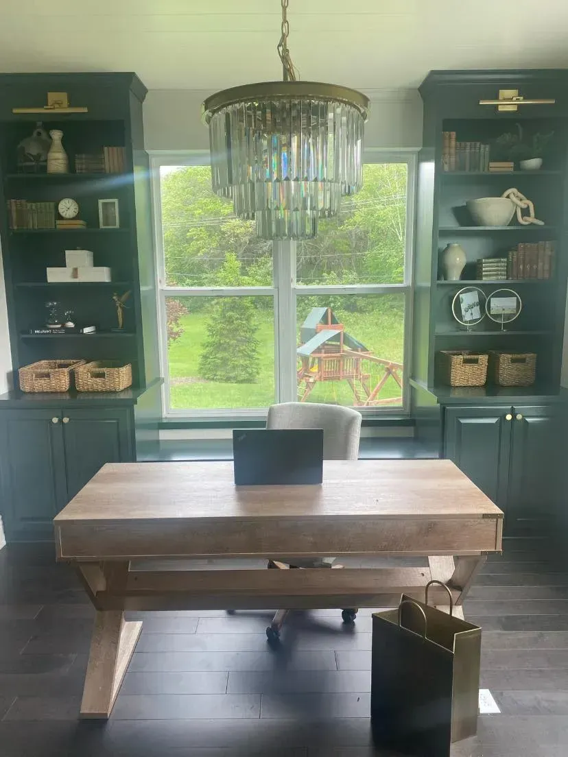 A desk with a laptop on it in a room with a large window.