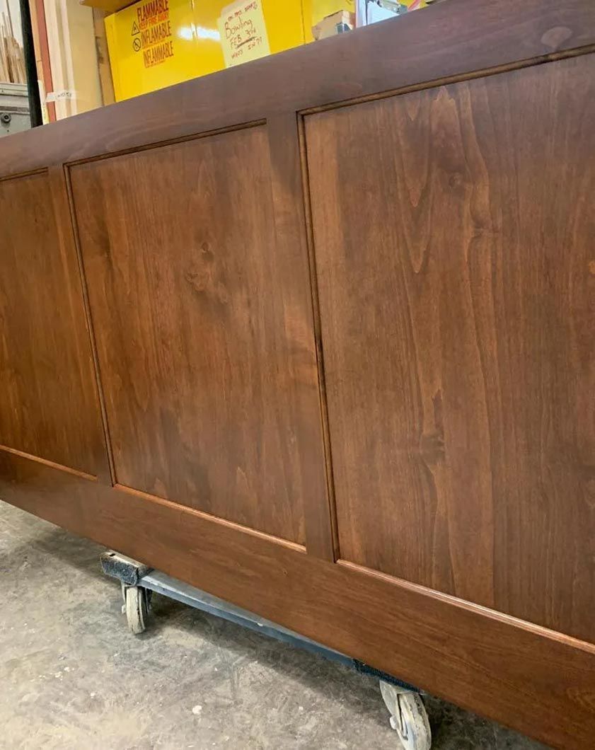 A wooden cabinet with wheels is sitting on the floor.