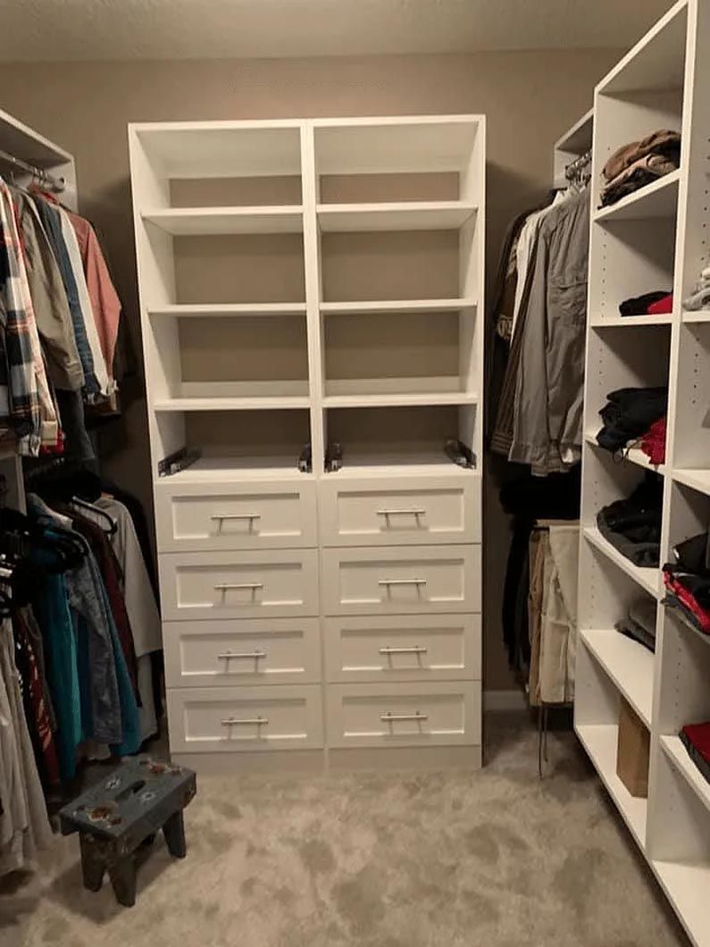 A walk in closet filled with lots of clothes and drawers.