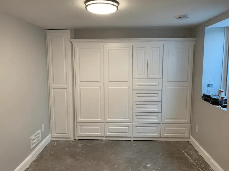 A room with a lot of white cabinets and drawers