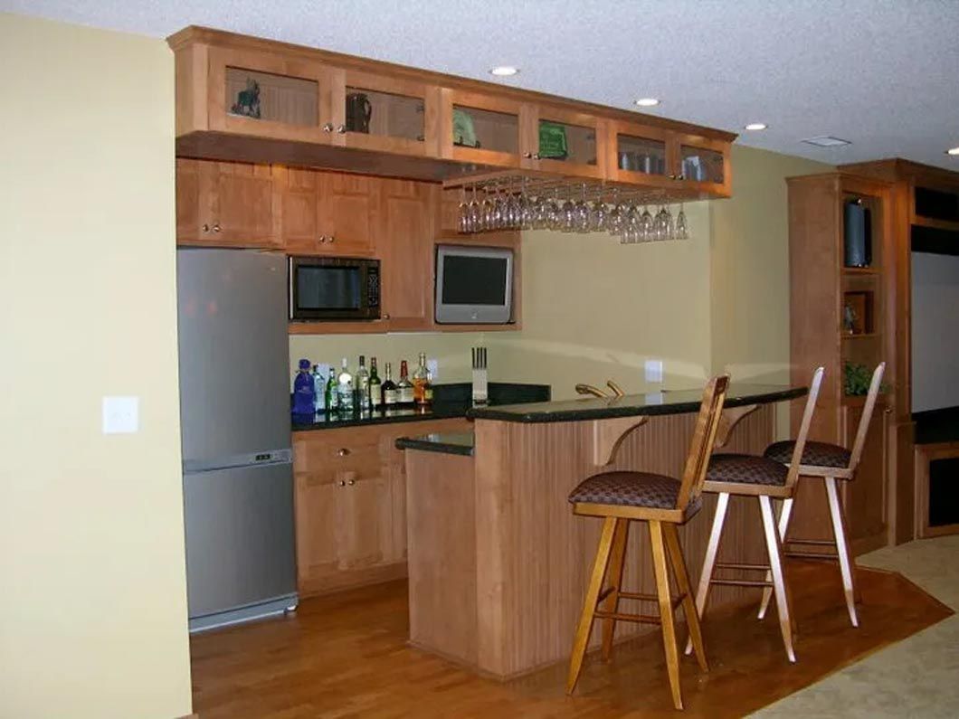 A kitchen with a bar and stools and a refrigerator
