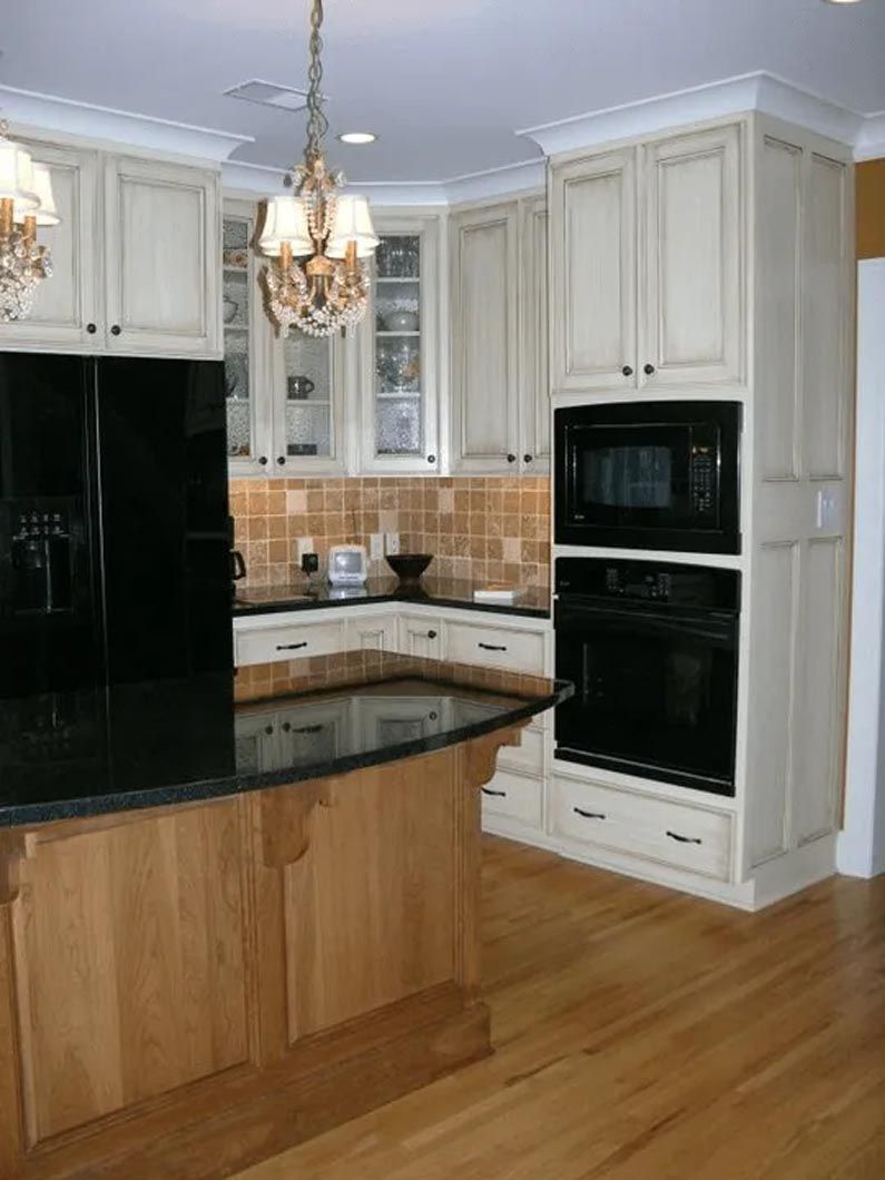 A kitchen with white cabinets and a black refrigerator