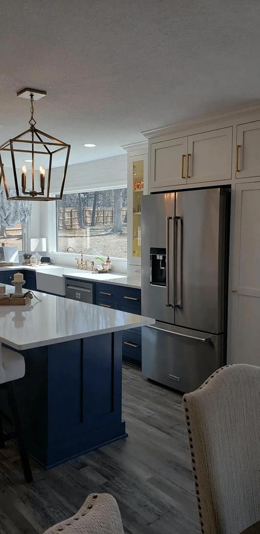 A kitchen with a stainless steel refrigerator and a blue island.
