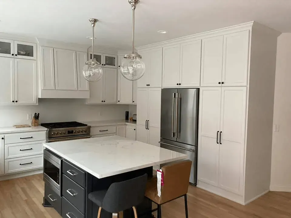 A kitchen with white cabinets , stainless steel appliances , and a large island.
