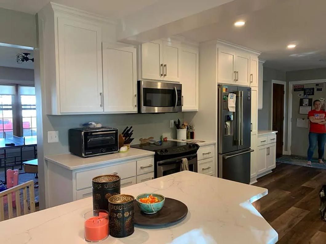 A kitchen with white cabinets , stainless steel appliances , and a large island.