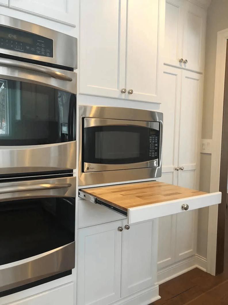 A kitchen with stainless steel ovens and a microwave.