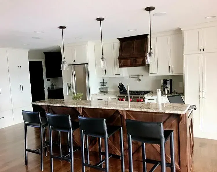 A kitchen with a large island , stools and a stove.