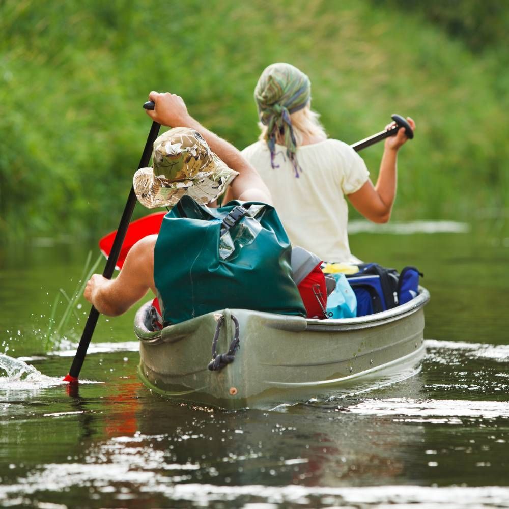 A man and a woman are paddling a canoe on a river