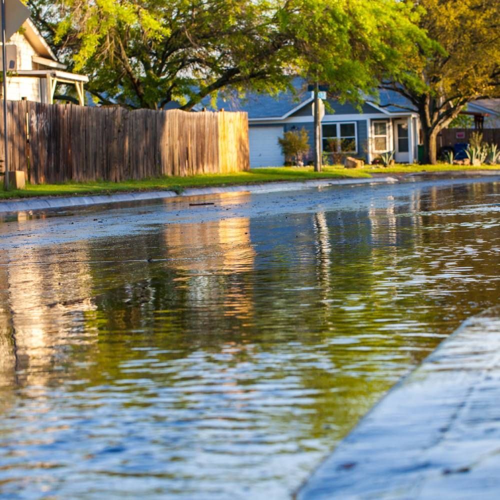 A flooded street with a house in the background