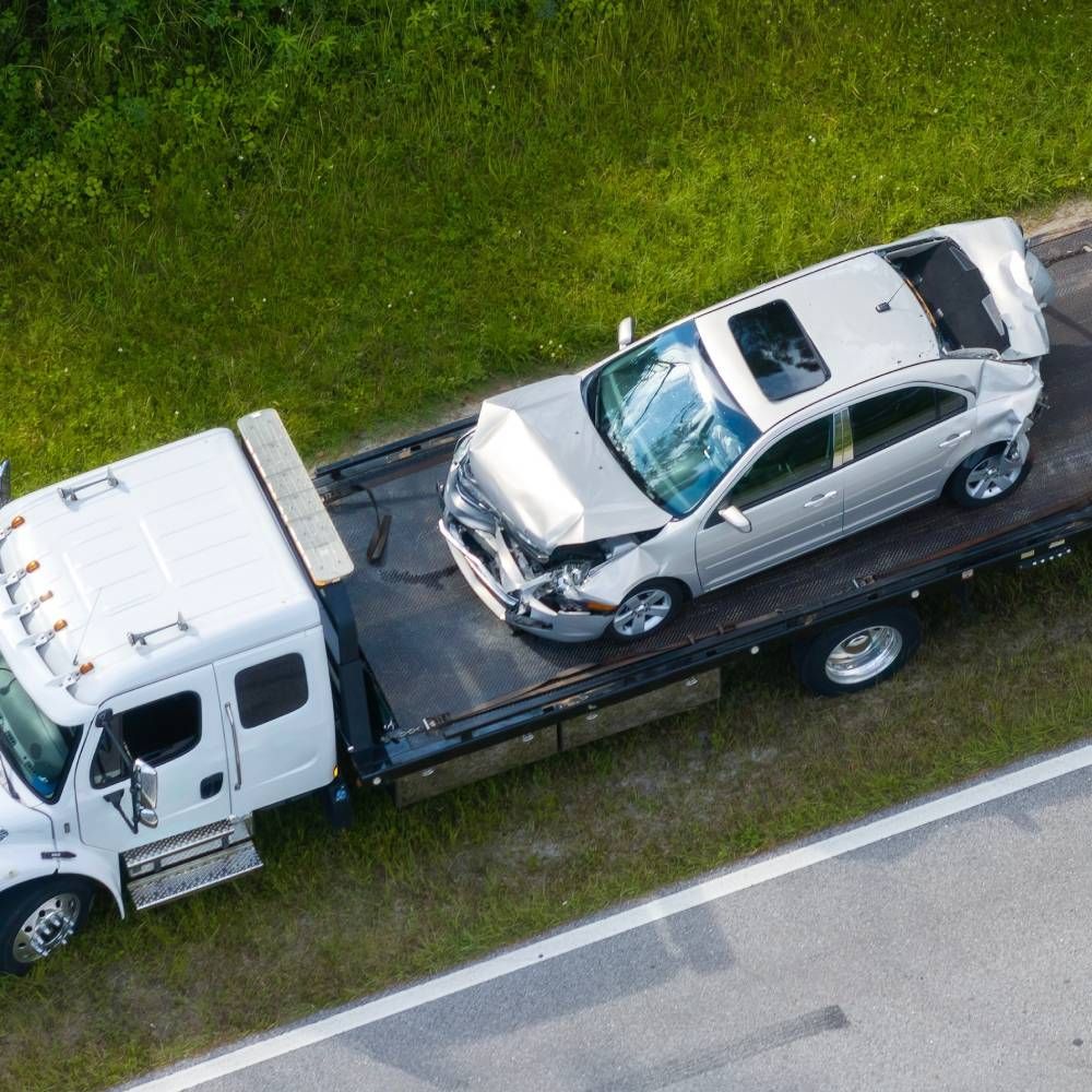 An aerial view of a tow truck with a car on the back.