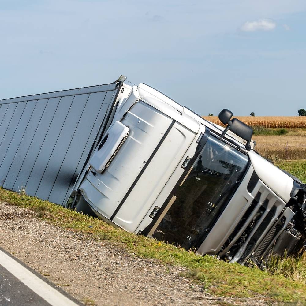 A semi truck has turned over on the side of the road