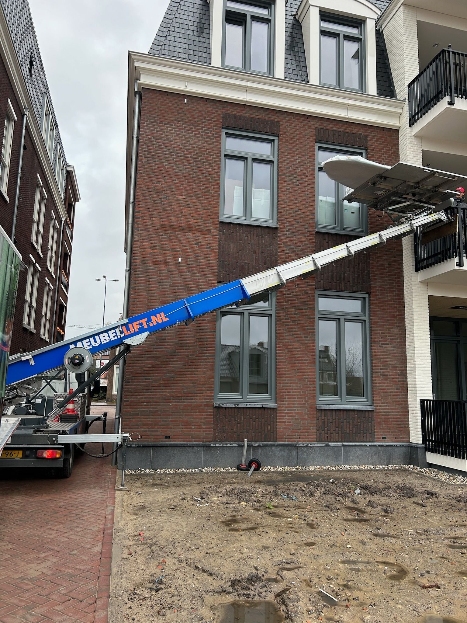 Een vrachtwagen staat geparkeerd voor een groot bakstenen gebouw.