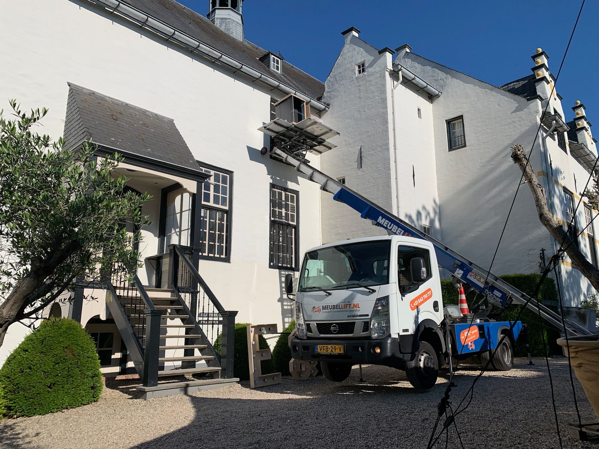 Een witte vrachtwagen staat geparkeerd voor een wit gebouw.