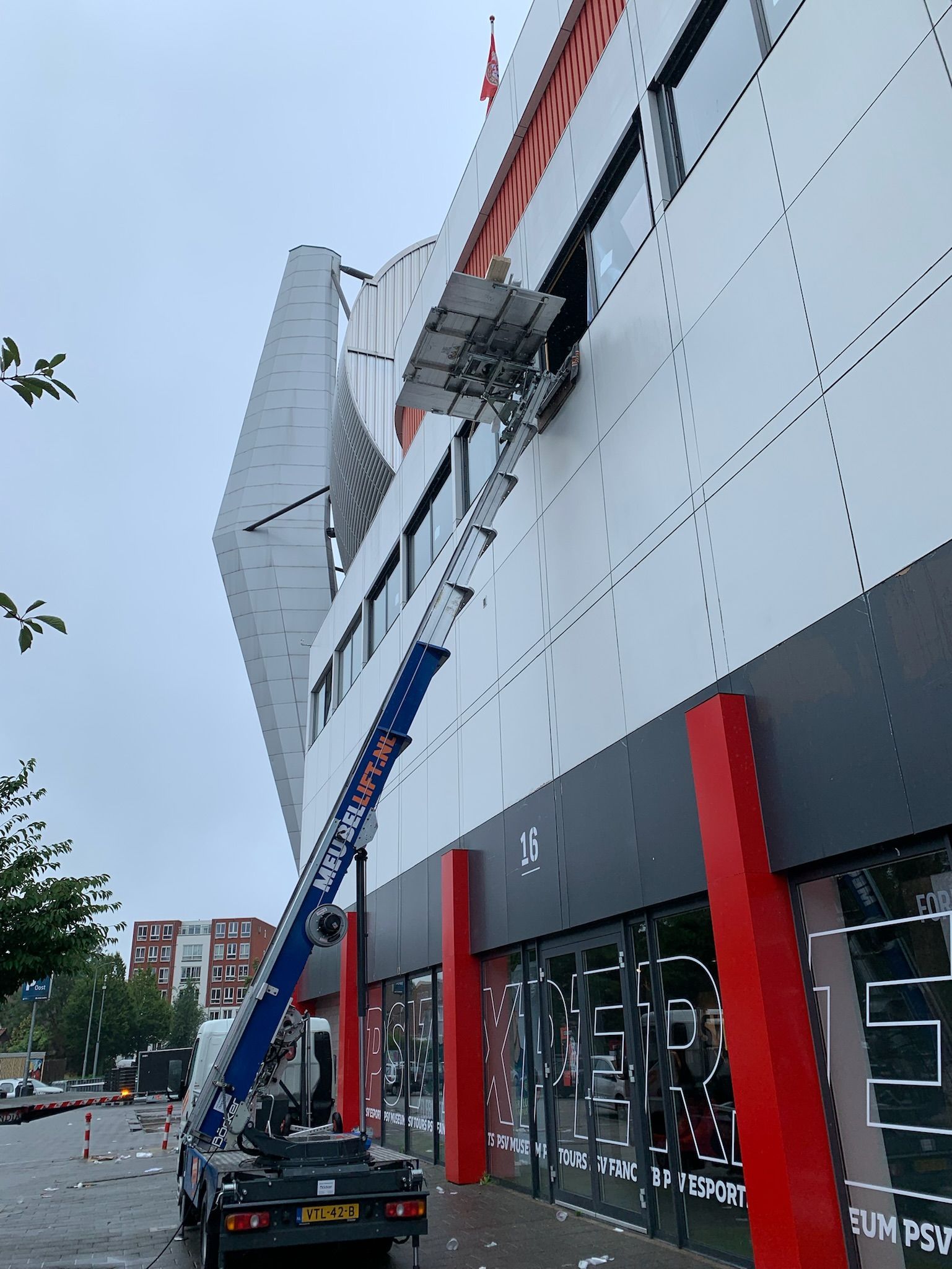 Een vrachtwagen met daaraan een ladder staat voor een gebouw geparkeerd.