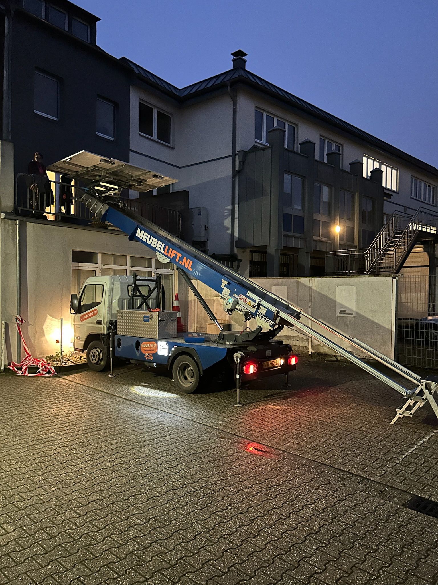 's Nachts staat er een kraan voor een gebouw geparkeerd.