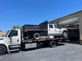 A white truck is being towed by a tow truck.