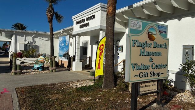 Visitor center and gift shop sign outside a white building at Flagler Beach, Florida.