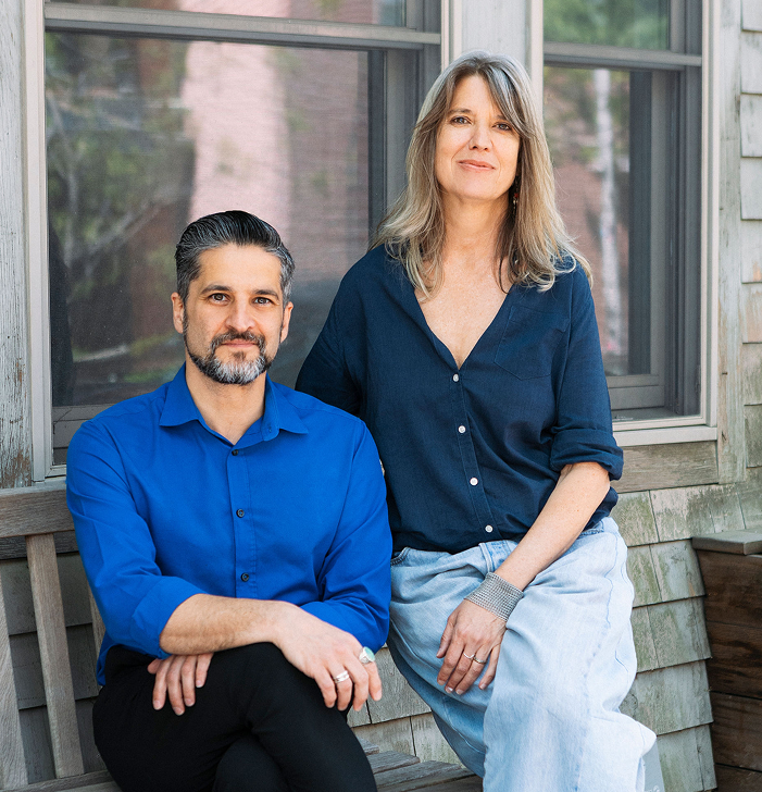 A man and a woman are sitting on a bench in front of a window.