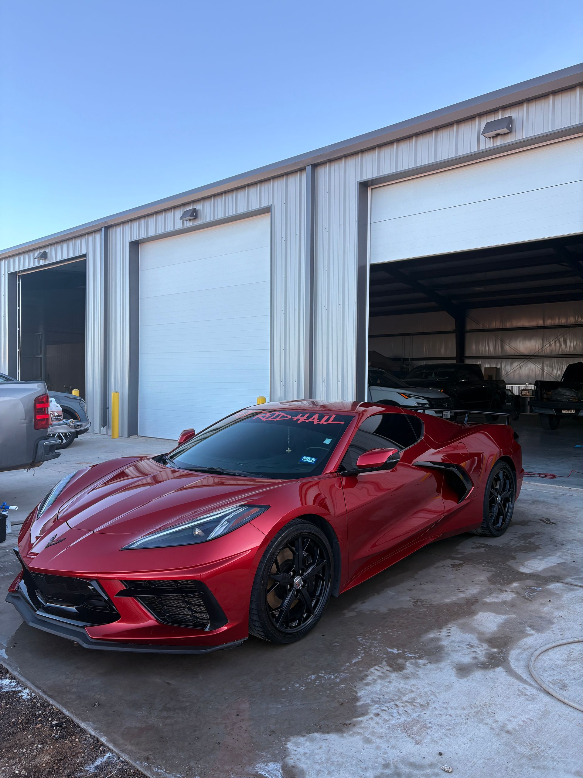 Red sports car parked outside an industrial garage with open bay doors