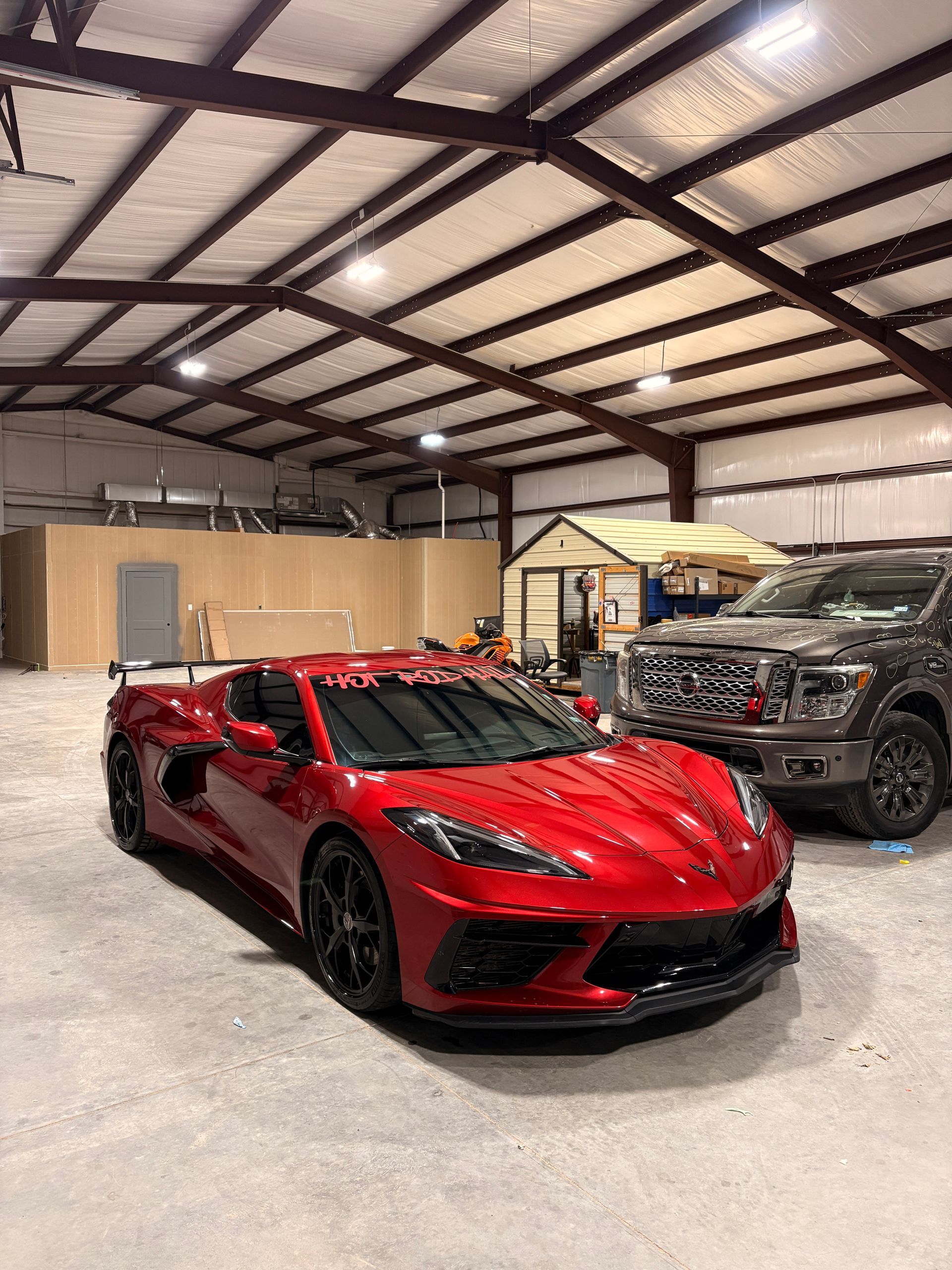 Red sports car and black SUV parked inside a large warehouse garage.