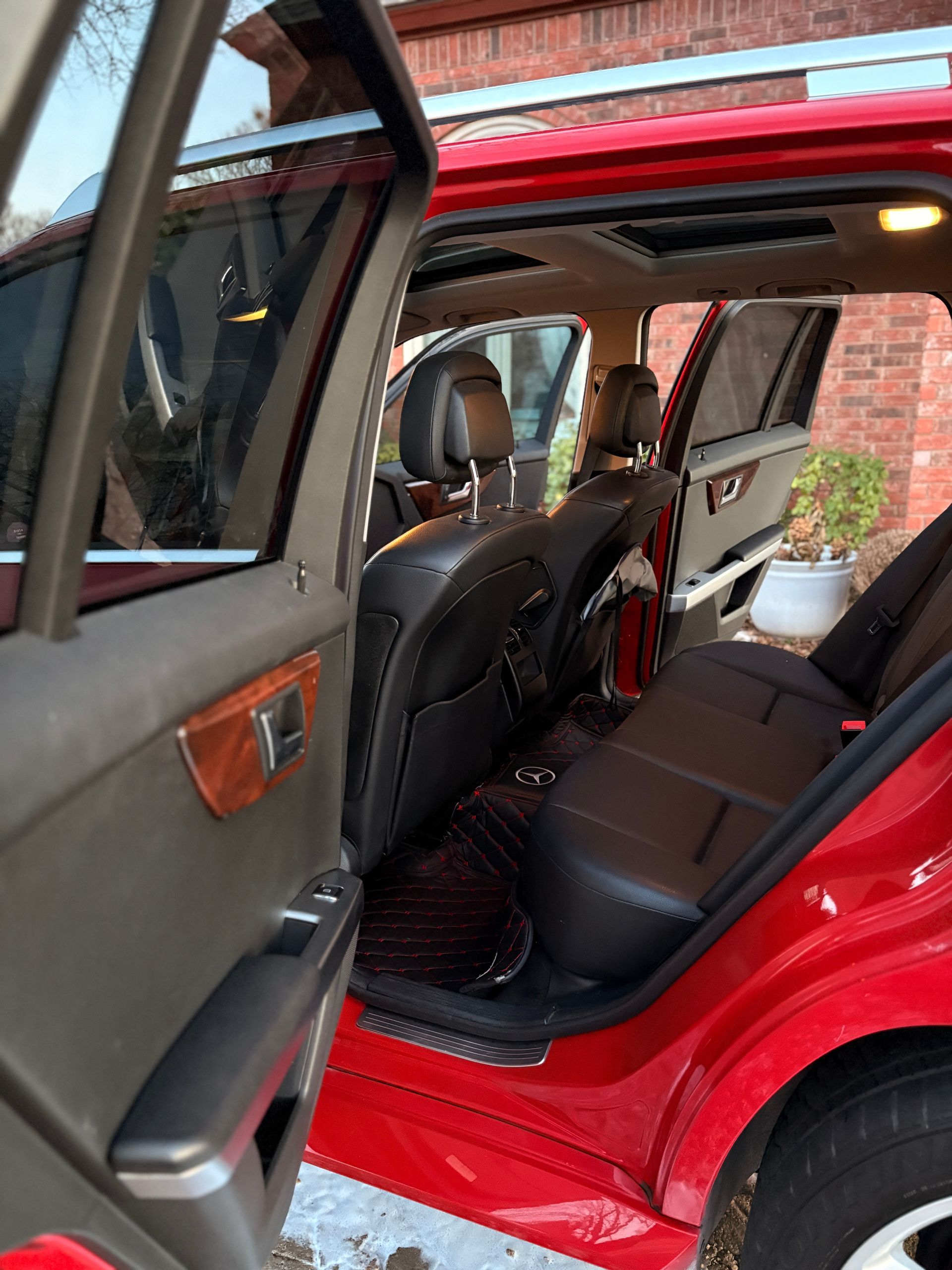 Open red car showing black leather back seat and open rear door in a driveway