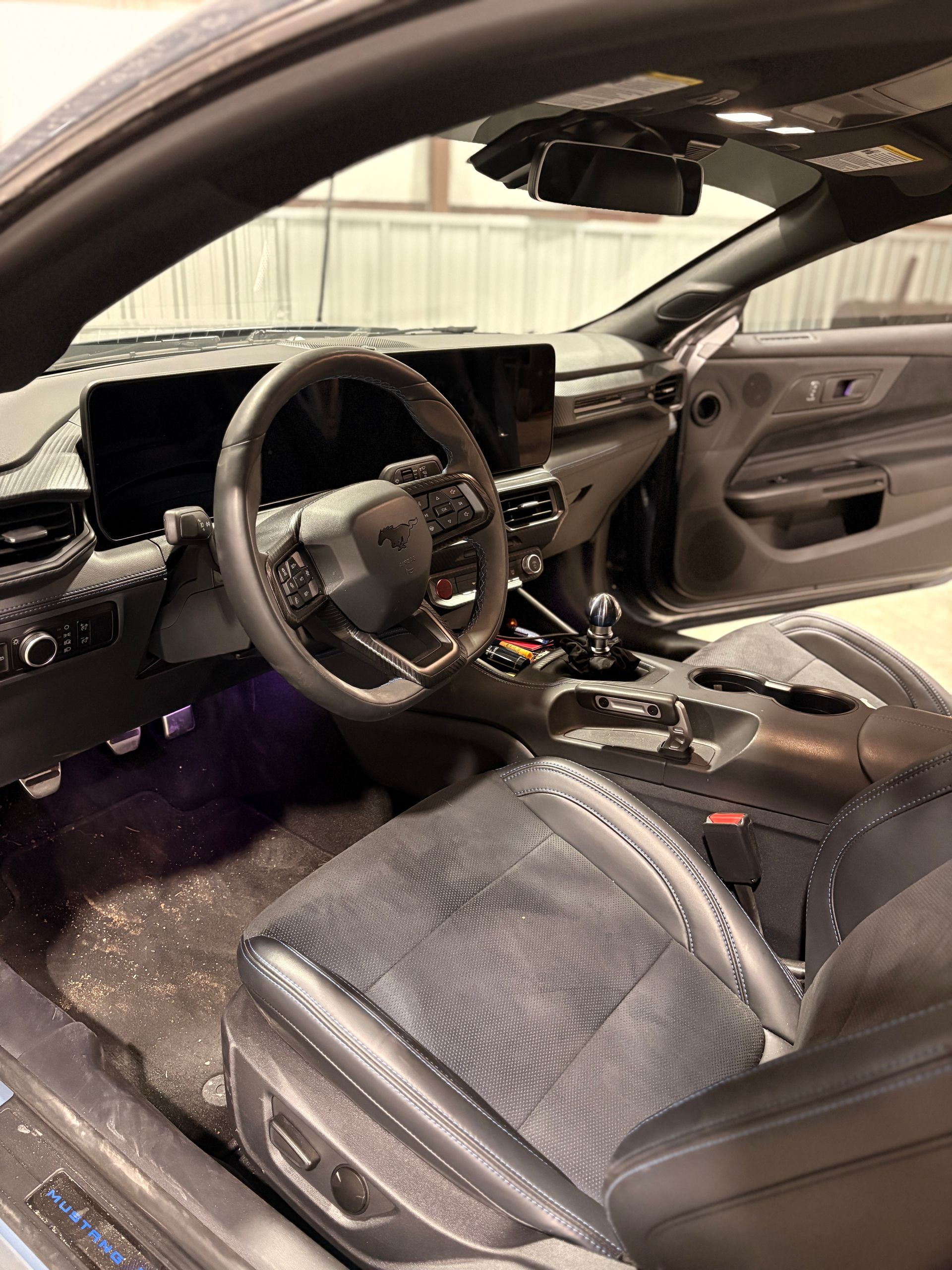 Car interior with deployed airbags, broken windshield, and shattered glass on the seat and floor.