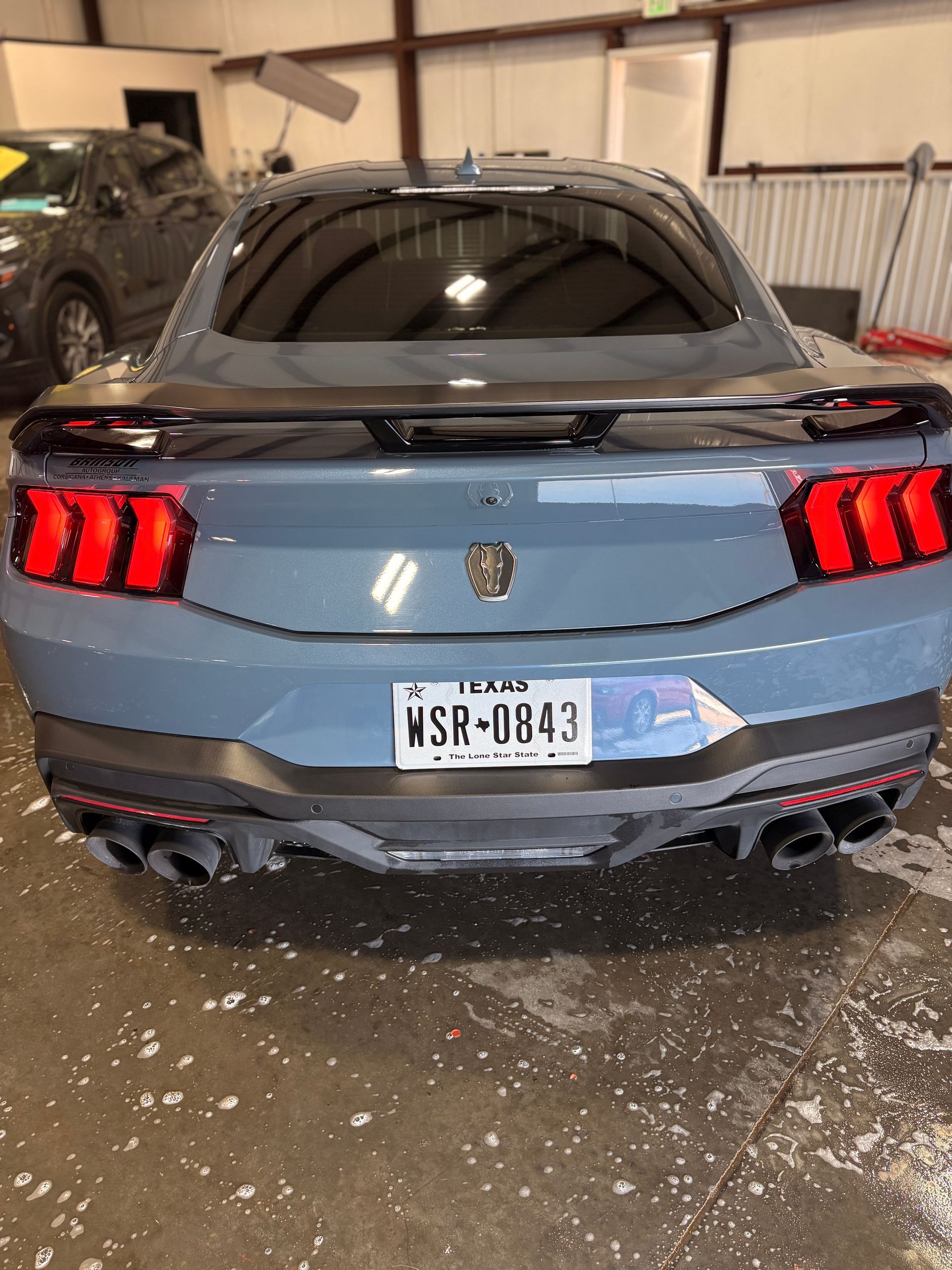 Blue sports car rear view with red taillights parked indoors on a wet floor