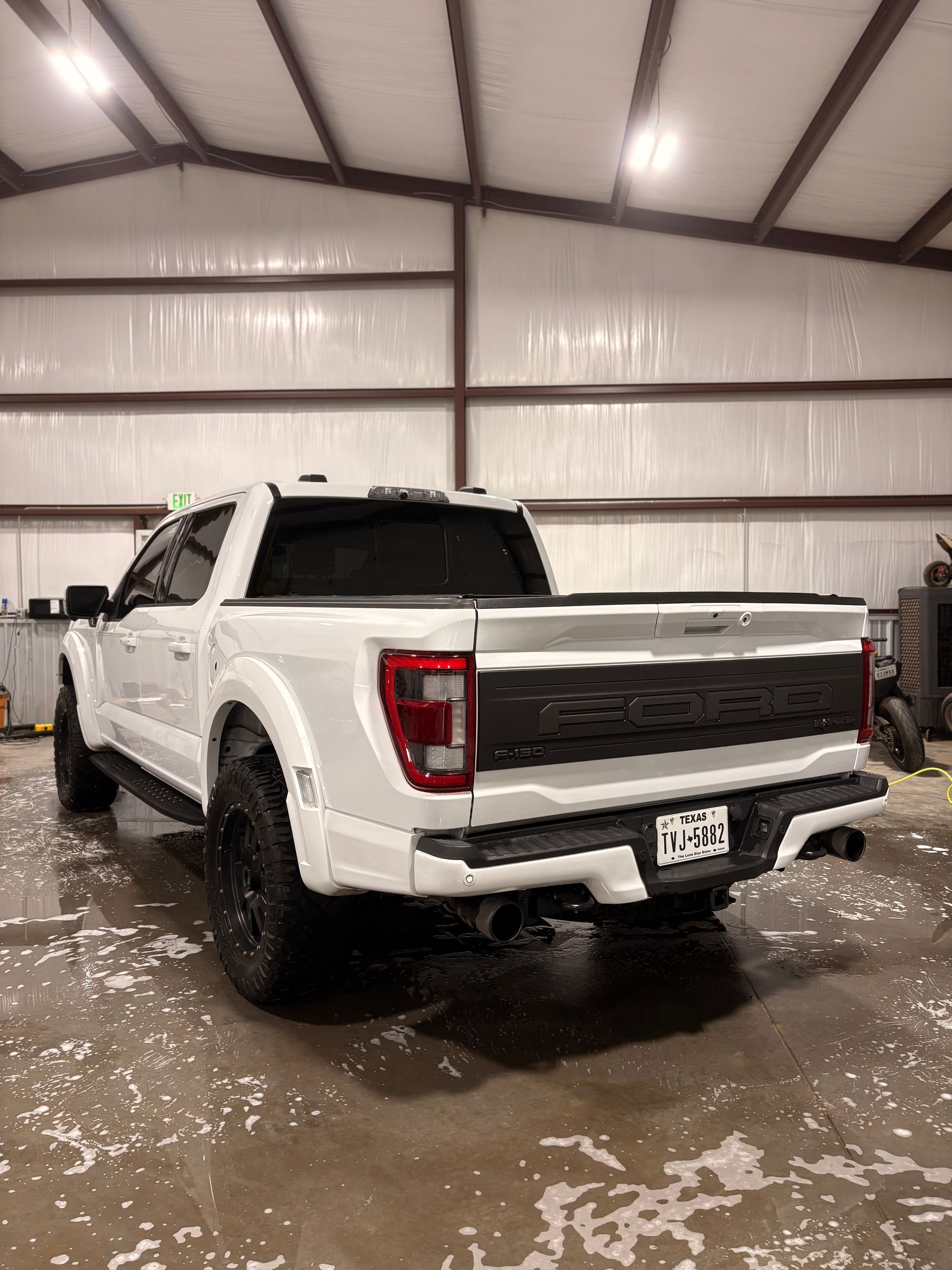 White pickup truck parked inside a garage with wet floor and snow around it