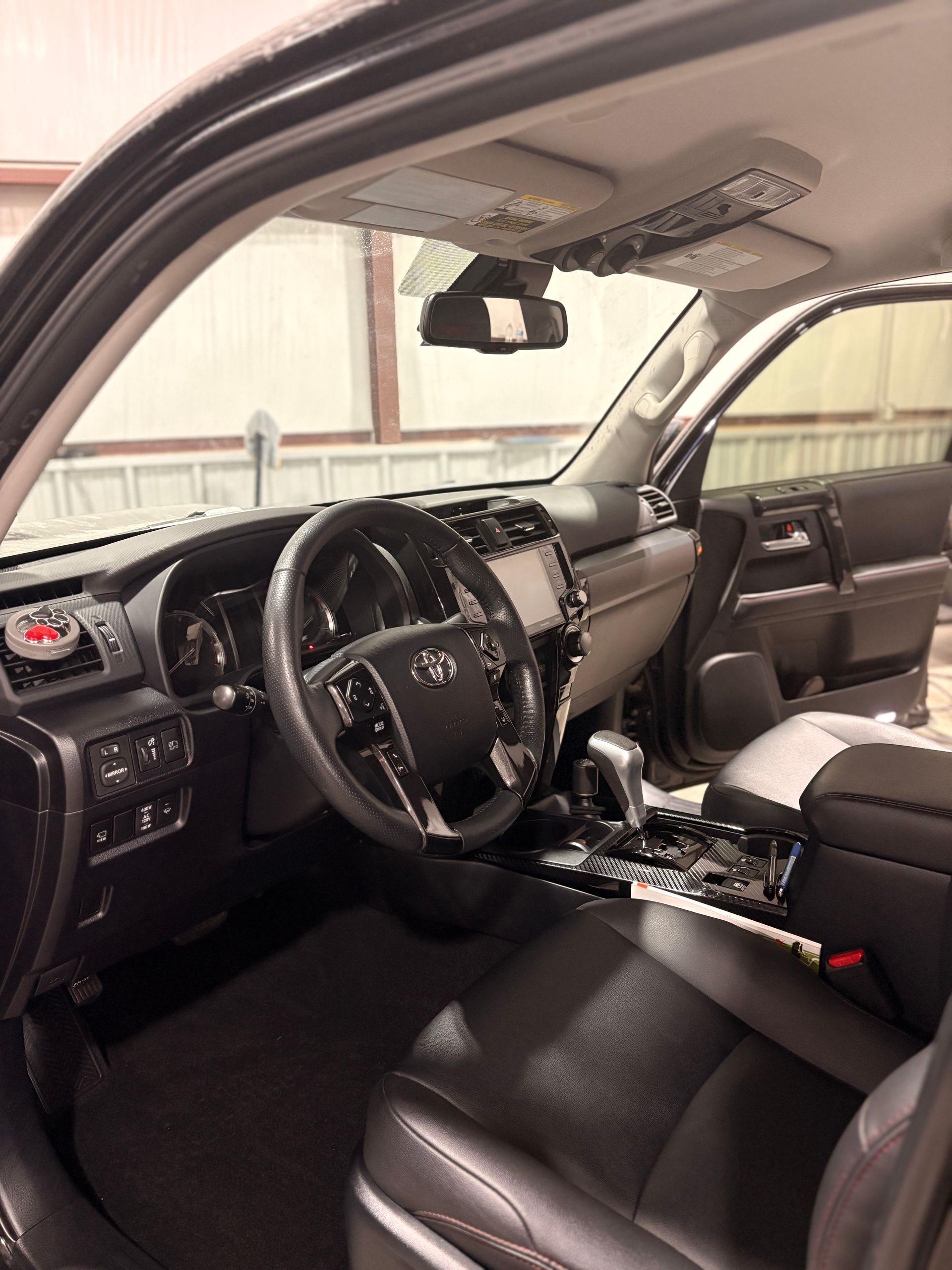 Interior of a black SUV, showing the dashboard, steering wheel, and leather seats with the door open.