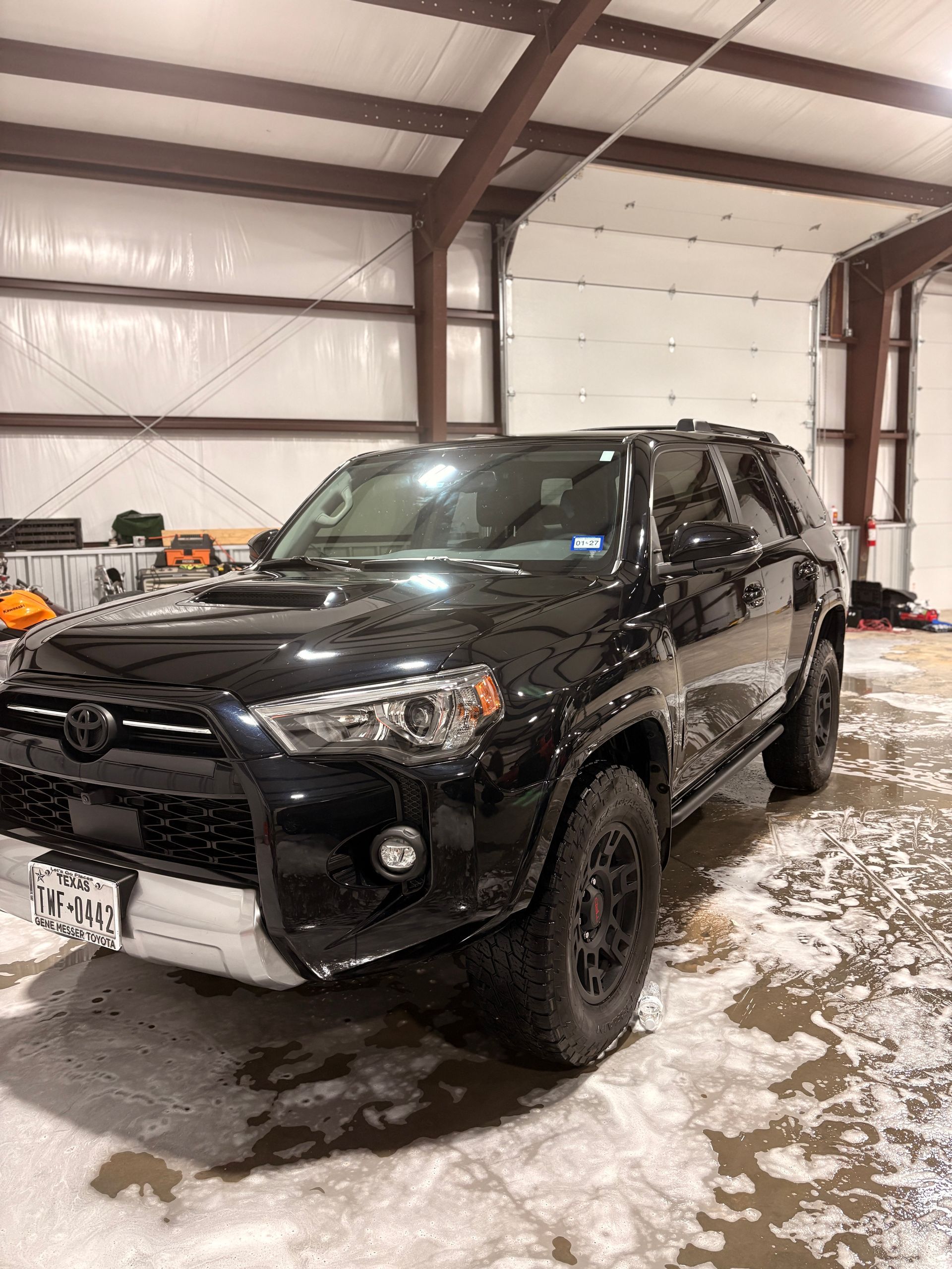 Black SUV parked inside a snowy garage with a white front snowplow blade attached