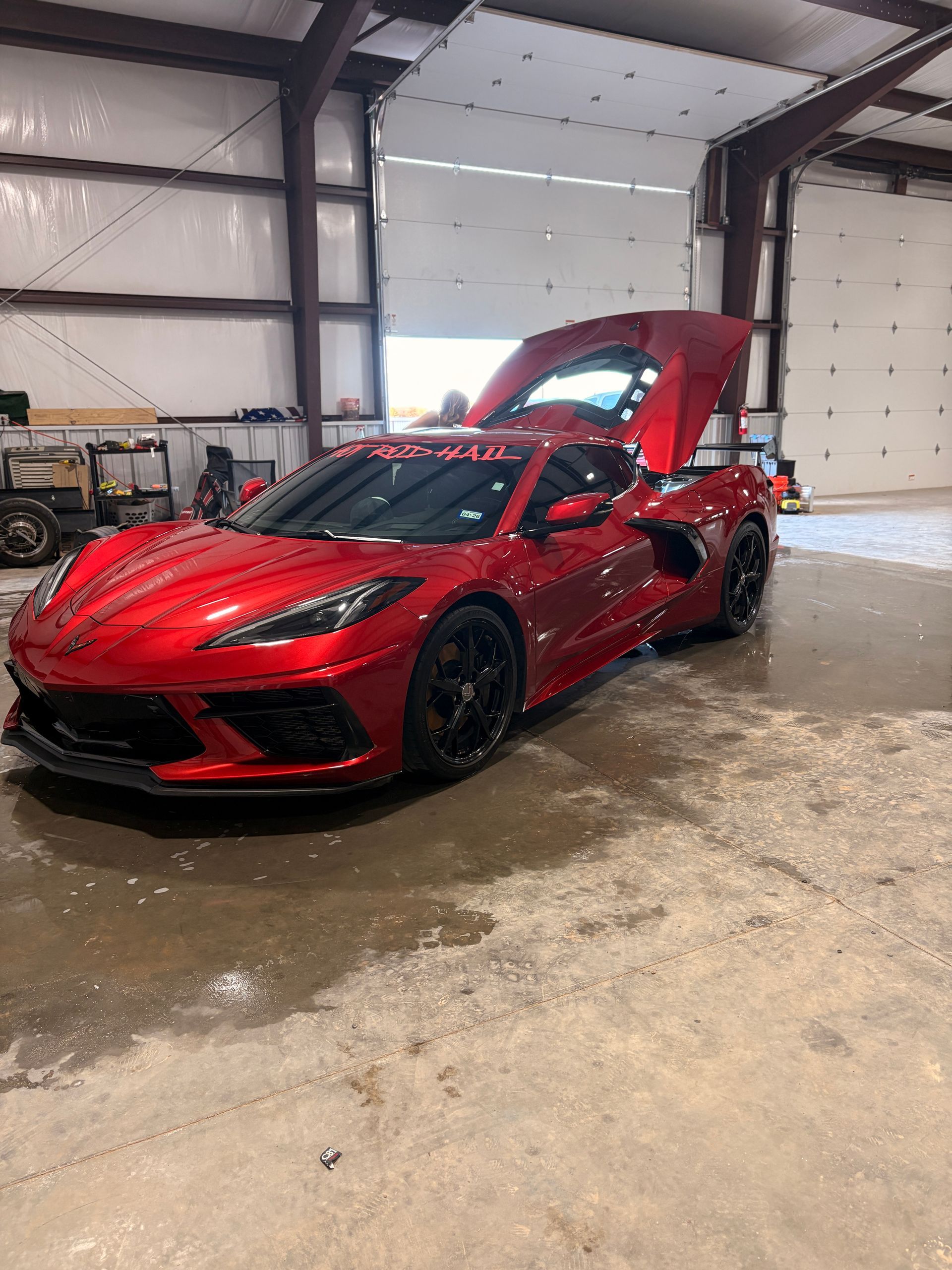 Red sports car with open hood in a garage, shiny wet floor and industrial interior