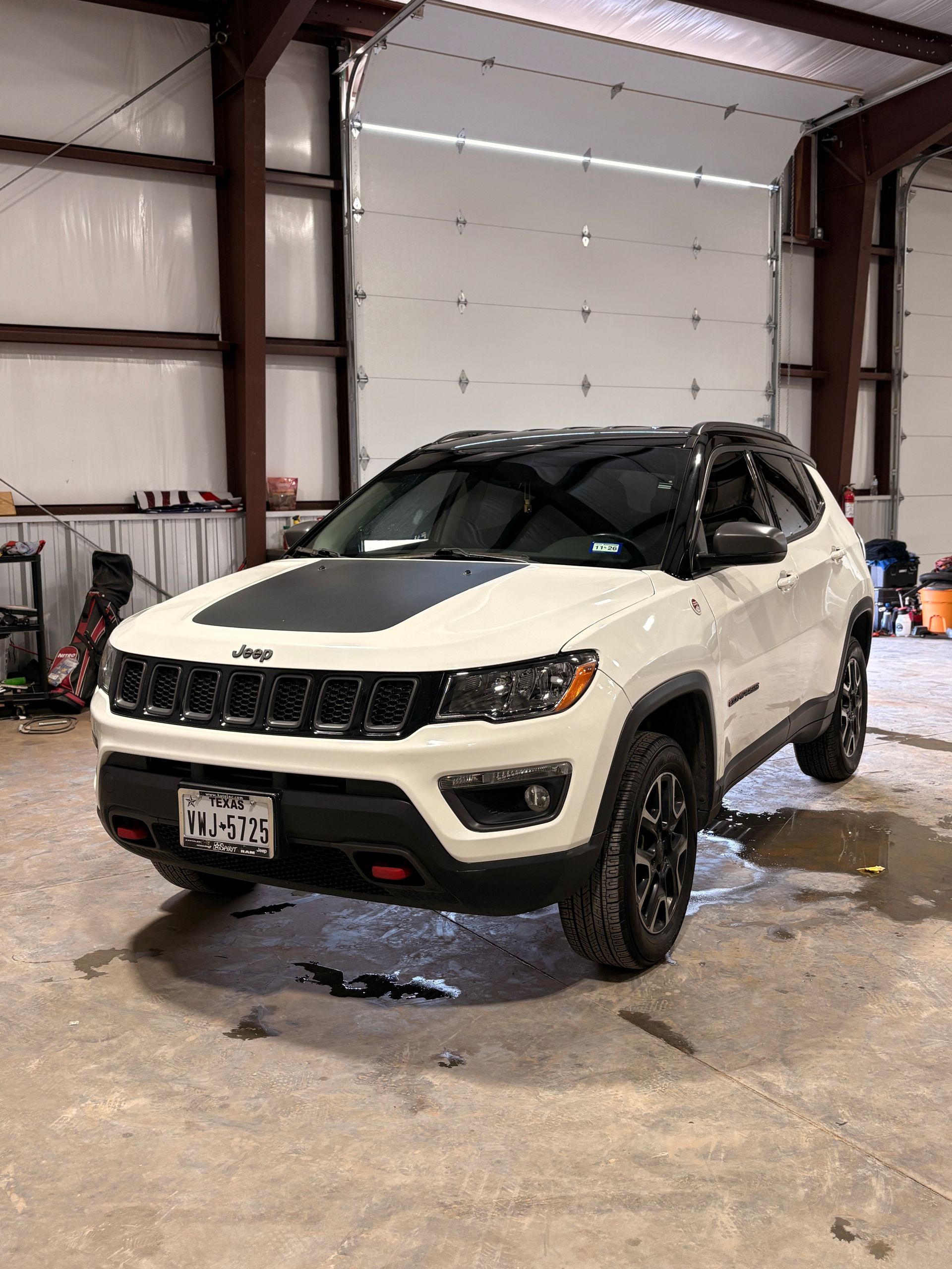 White SUV in a garage, angled front view with wet floor and industrial interior.