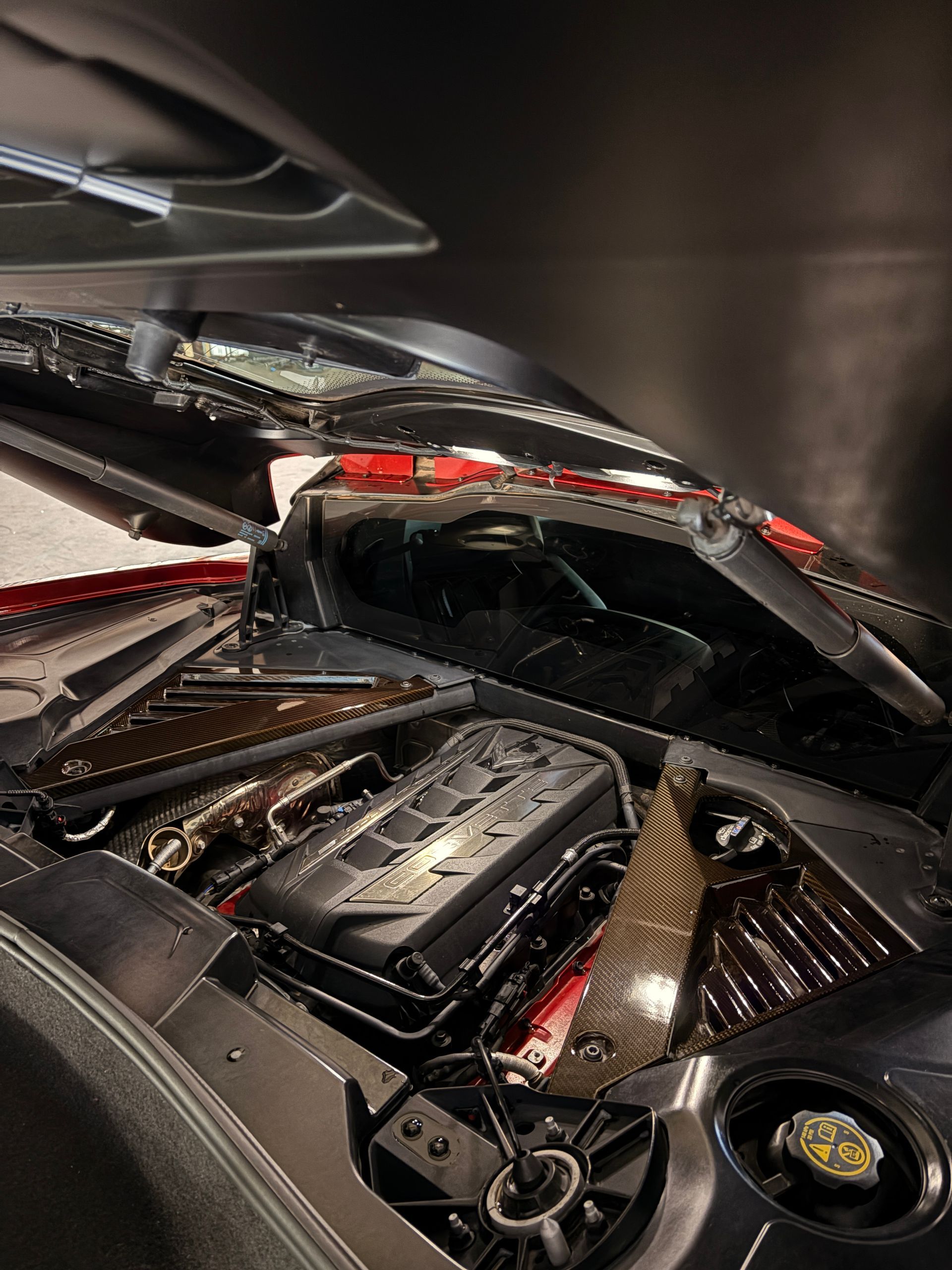 Severely damaged black sports car interior with shattered windshield and crushed roof in a garage or shop