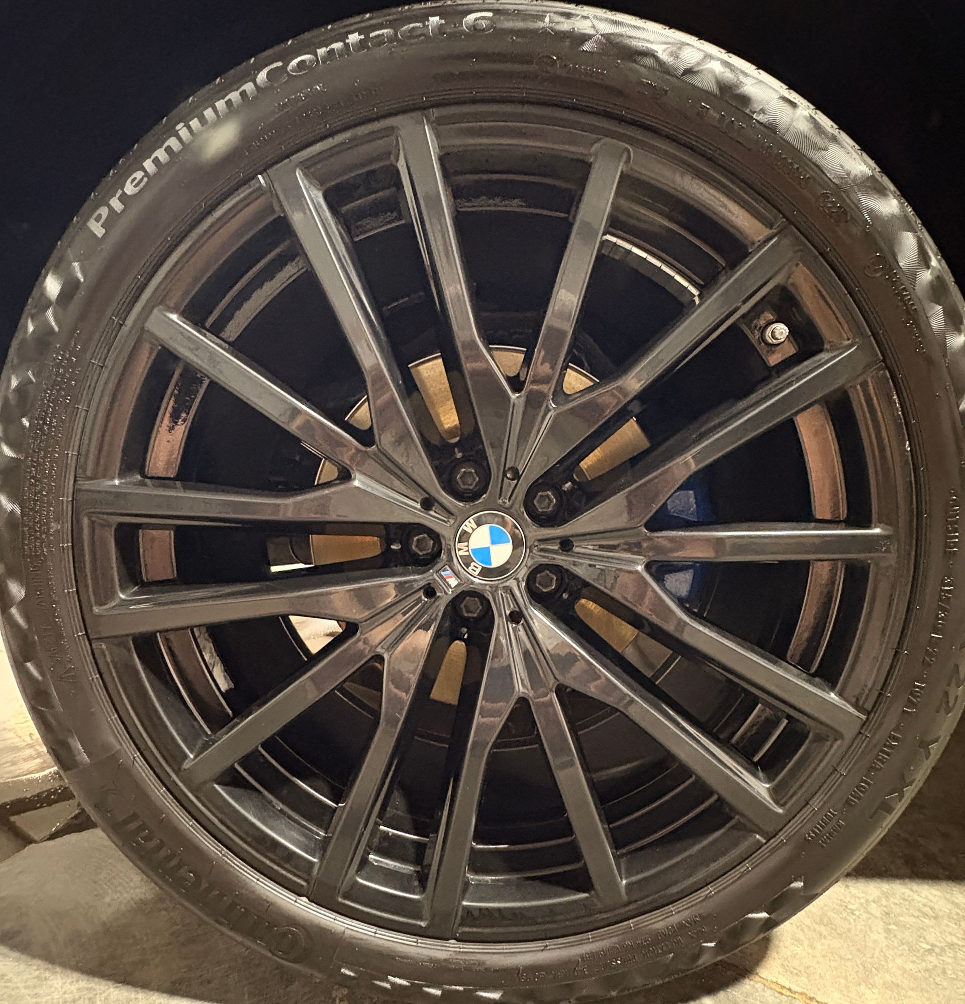 Black BMW alloy wheel and tire close-up, with scuffed rim and BMW logo center cap
