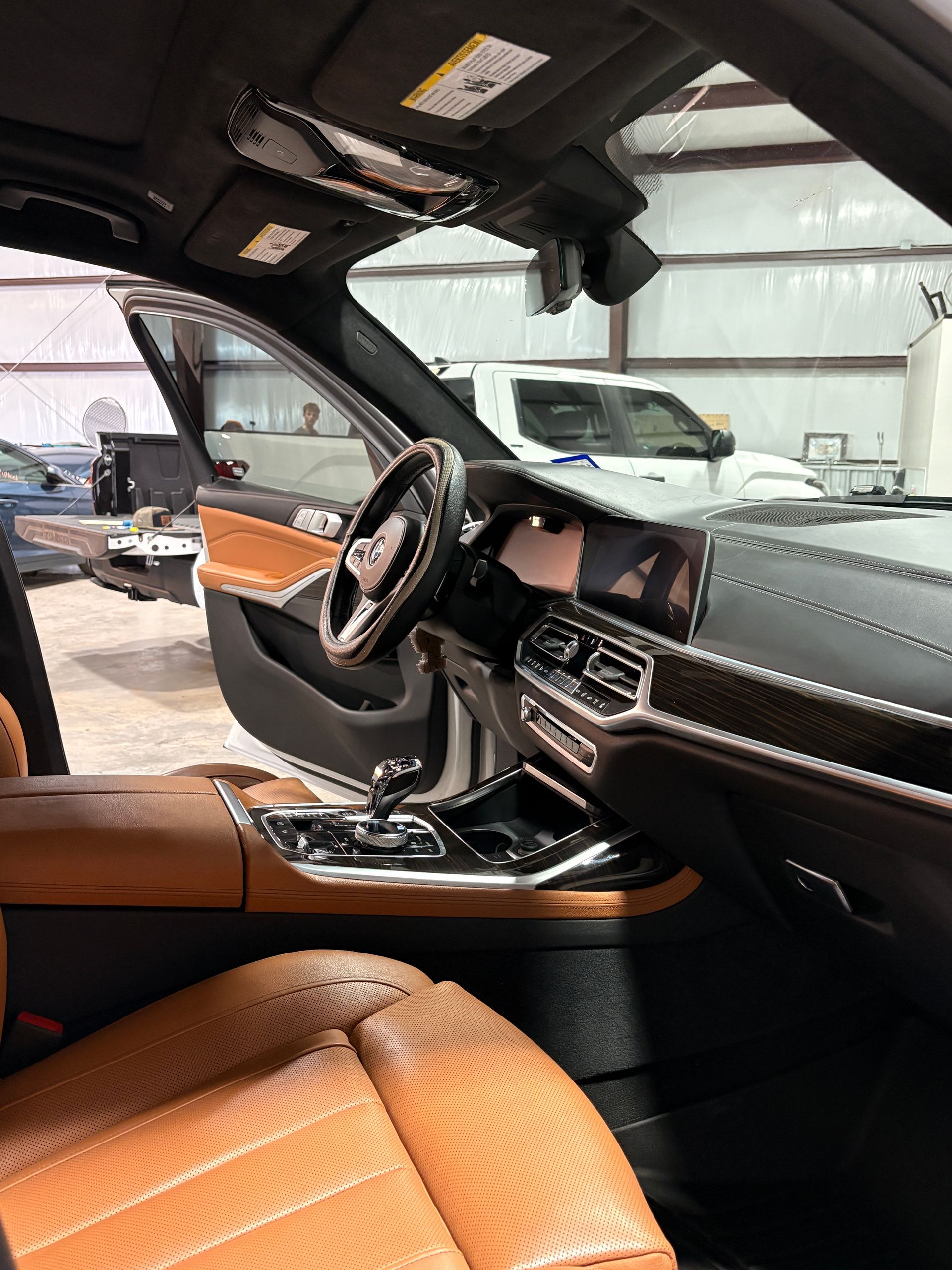 Car interior with tan leather seats, black dashboard, and panoramic roof, viewed from the passenger side