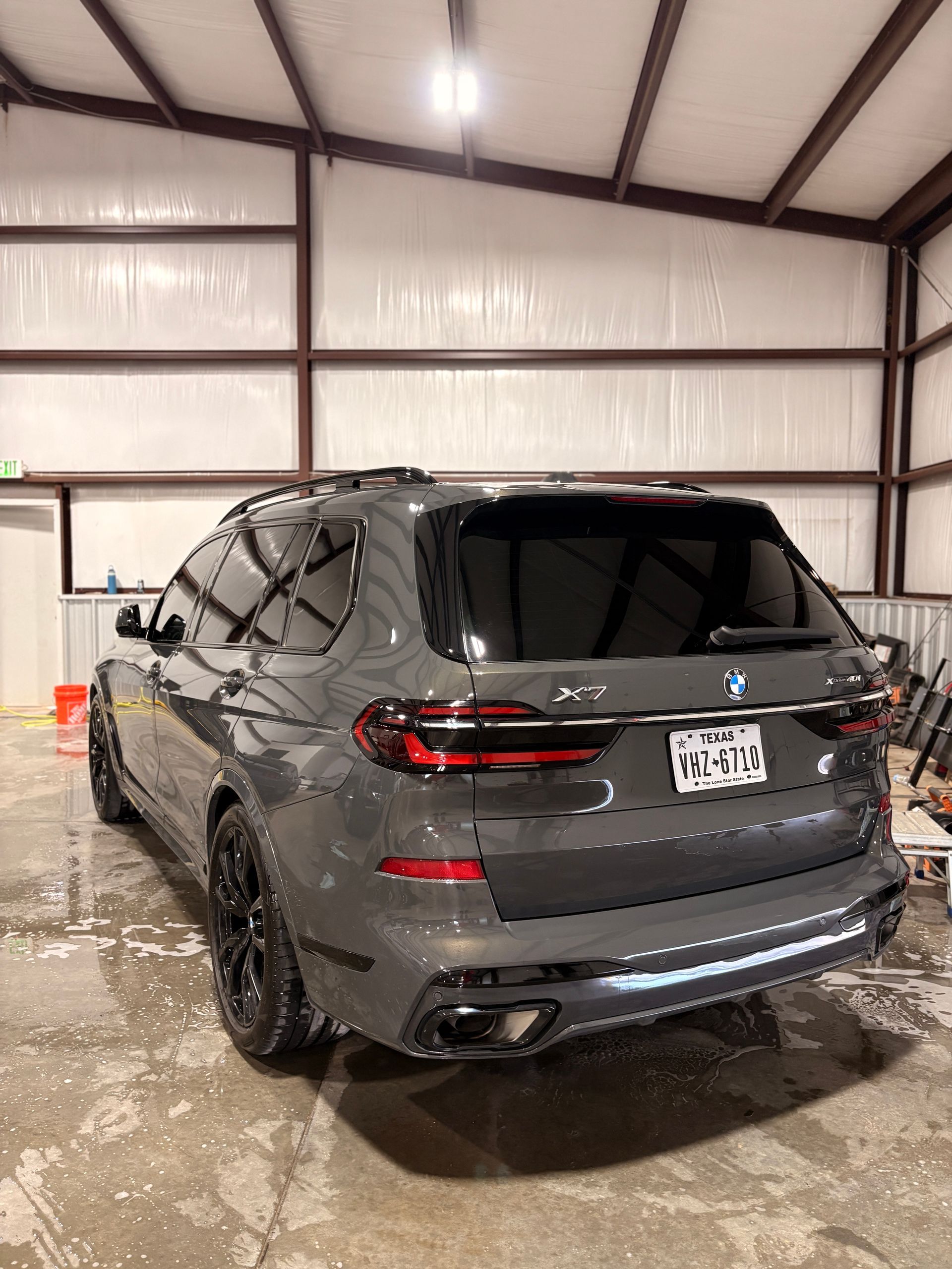 Dark gray SUV parked inside a wet metal garage, rear view.