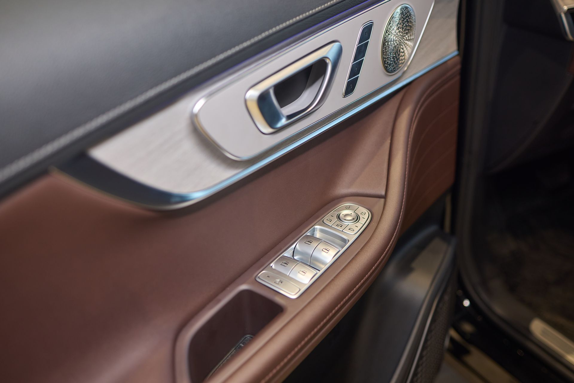 Car door interior with brown leather trim, silver handle, and window control buttons
