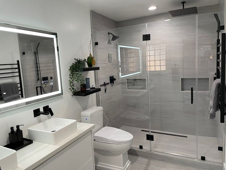 A bathroom with a toilet , sink , mirror and walk in shower.