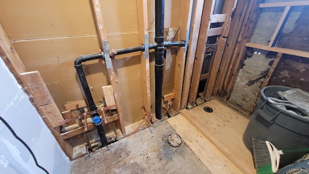 A bathroom under construction with pipes coming out of the wall.