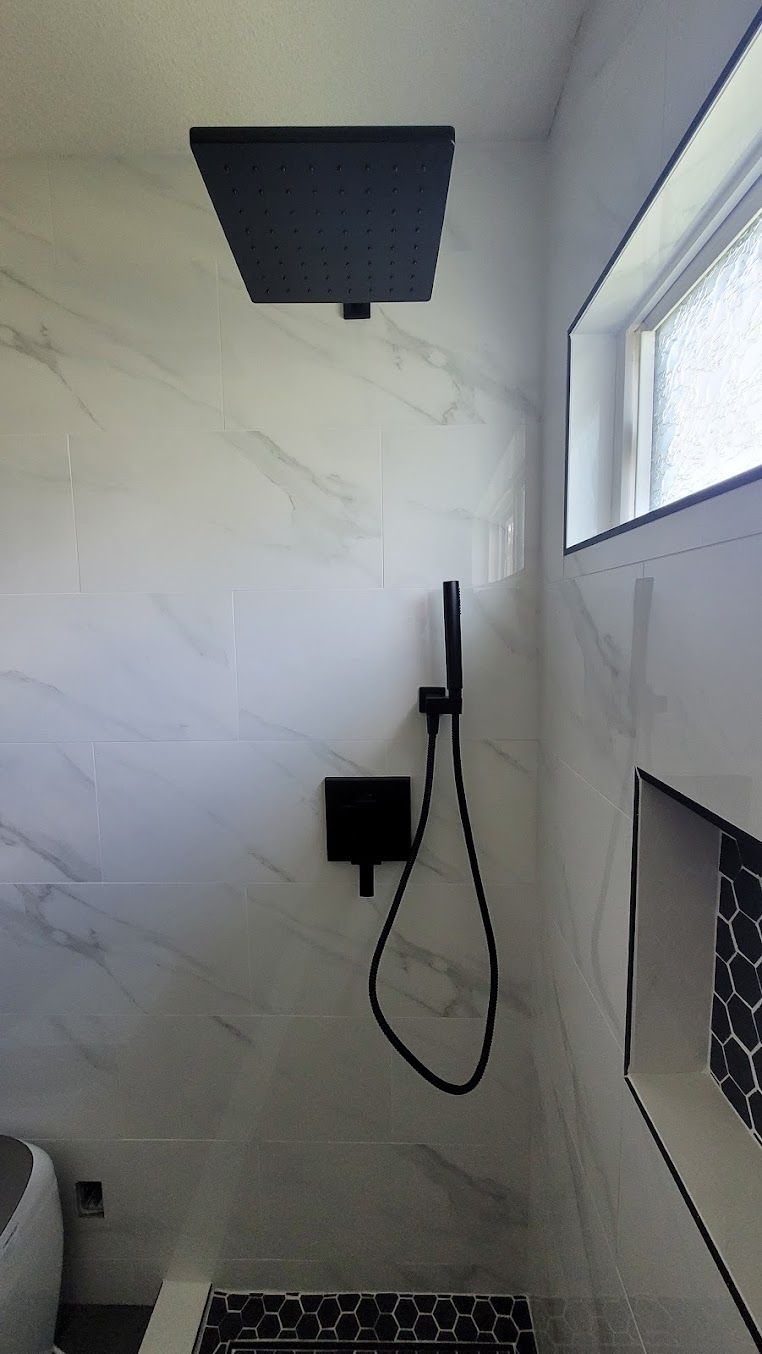 A bathroom with a shower head and a window.