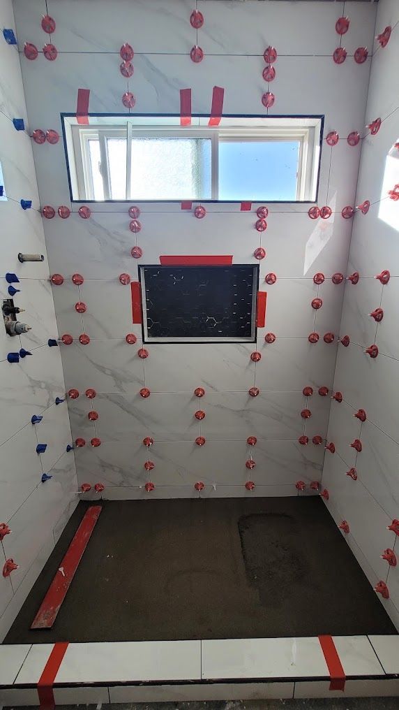 A bathroom is being remodeled with tiles and a window.