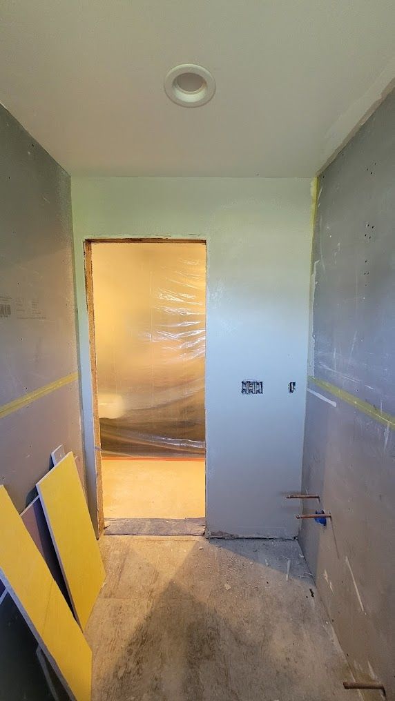 A bathroom under construction with a door and a ceiling light.
