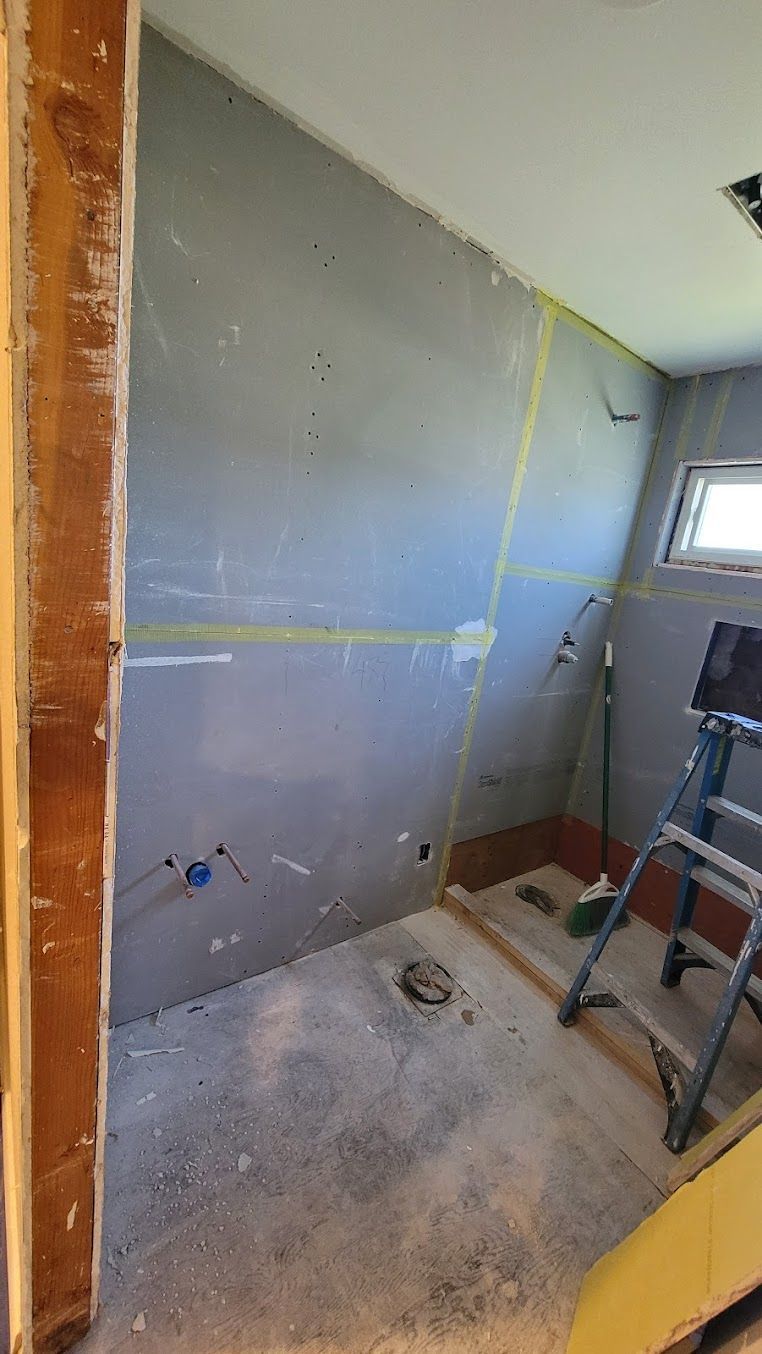 A bathroom under construction with a ladder and a broom.