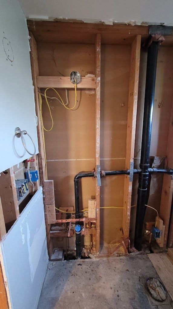 A bathroom under construction with a lot of pipes coming out of the wall.
