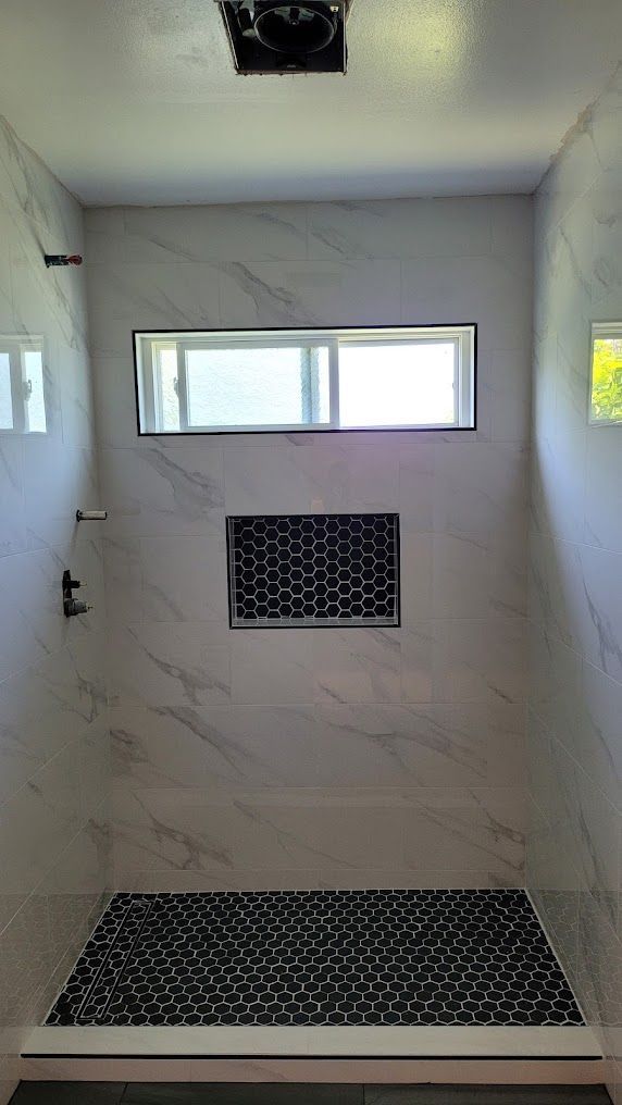 A bathroom with a walk in shower and a window.