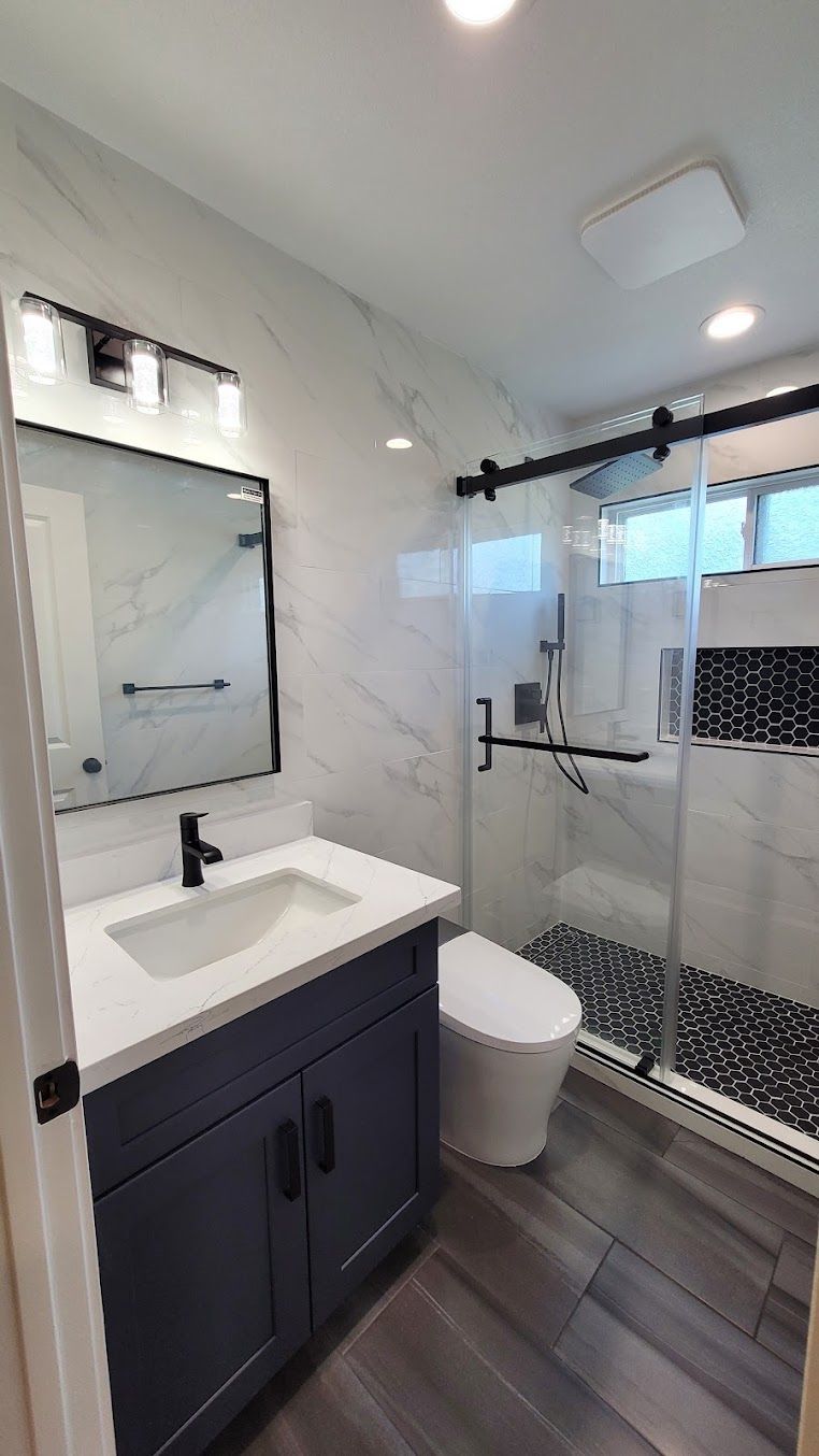 A bathroom with a sink , toilet , shower and mirror.