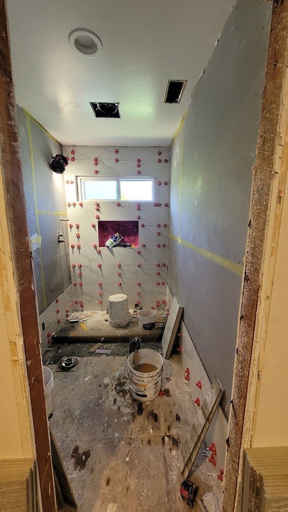 A bathroom under construction with a bucket of water on the floor.