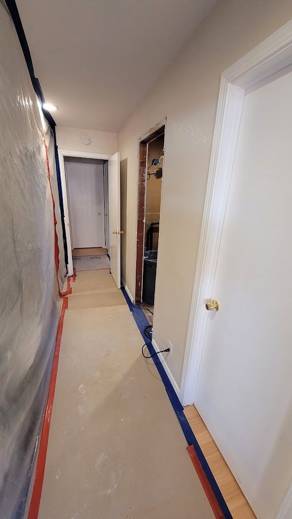 A long hallway with a lot of doors and a blue tape on the floor.