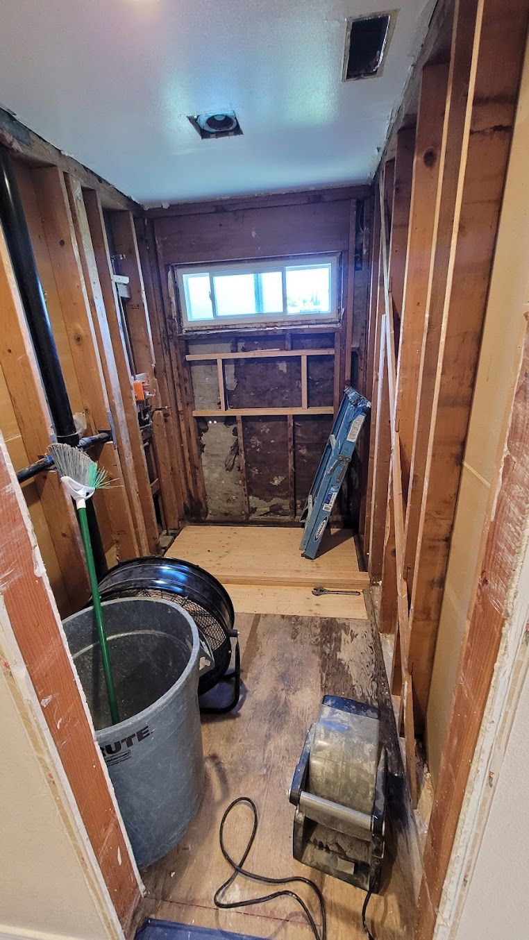 A bathroom under construction with a bucket of water and a fan.