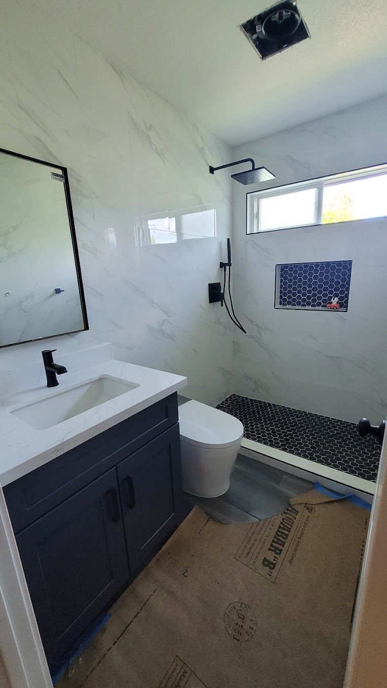 A bathroom with a sink , toilet , shower and mirror.